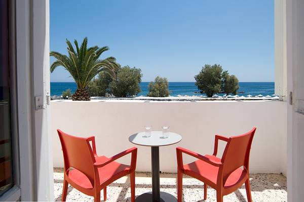 Terrasse des Beach Boutique Hotels mit Blick auf das Meer und roten Stühlen.