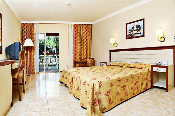 Hotelzimmer im Kustur Club Holiday Village mit Bett, Schreibtisch, Fernseher und Balkon.