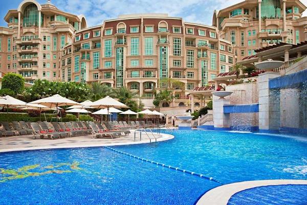 Außenpool des Swissotel Al Murooj Dubai mit Lounge-Sesseln und Sonnenschirmen