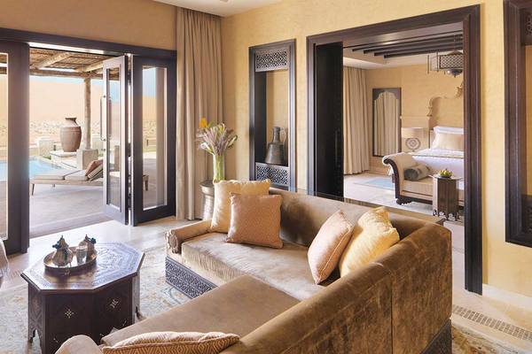 Innenansicht des Qasr Al Sarab Desert Resort by Anantara mit Wohnzimmer, Couch, und Aussicht auf die Wüste.