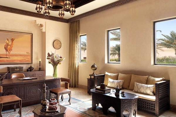 Wohnzimmer im Qasr Al Sarab Desert Resort by Anantara mit Sofa, Tisch, Gemälde und Fenstern.
