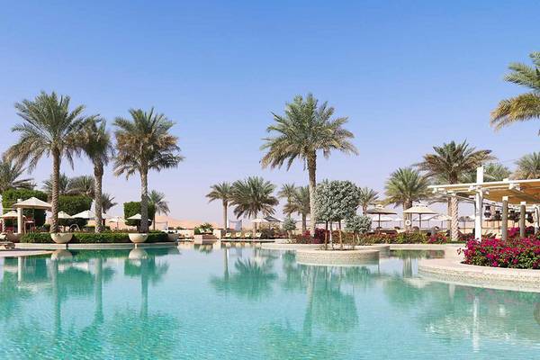 Außenpool des Qasr Al Sarab Desert Resort von Anantara mit Palmen und Sonnenschirmen