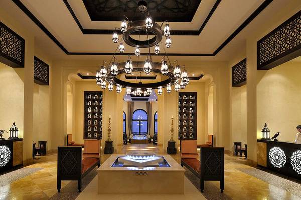 Empfangshalle des Qasr Al Sarab Desert Resort mit großer Kronleuchter und Rezeptionstresen.