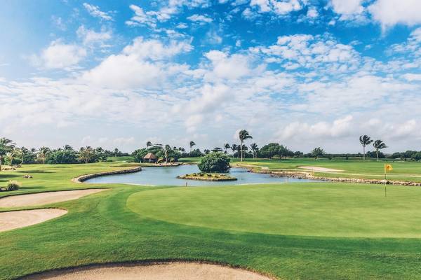 Golfplatz beim Iberostar Selection Cancun Hotel mit Wasserhindernis und Palmen
