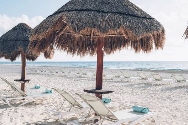 Strand mit Sonnenliegen und Strohhüten am Iberostar Selection Cancun