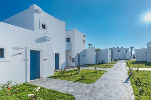 Außenansicht des Aeolos Beach Hotel auf Kos mit weißen Gebäuden und blauen Türen.