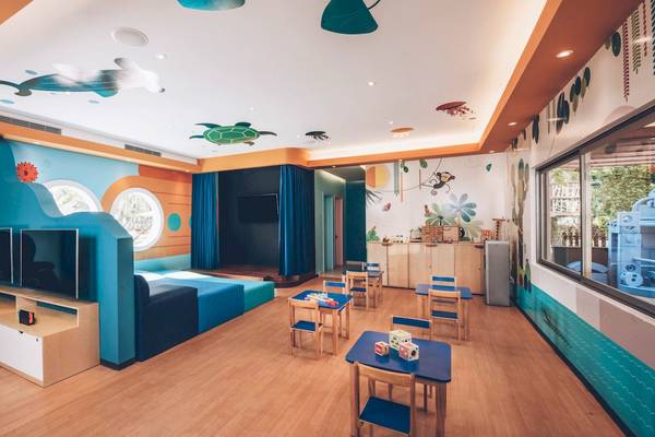 Kinderzimmer im Iberostar Selection Cancun mit blauen Möbeln, Fernsehern, bunten Wandmalereien und Spielzeug.