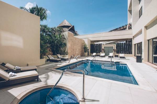 Außenpoolbereich des Iberostar Selection Cancun Hotels mit mehreren Sonnenliegen und einer kleinen Whirlpool-Ecke.