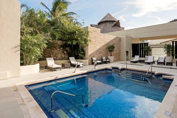 Außenpool-Loungebereich des Iberostar Selection Cancun Hotels mit Lounge-Stühlen und Pflanzen
