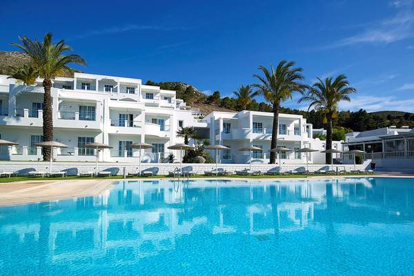 Außenbereich des Dimitra Beach Hotel & Suites mit Swimmingpool und Sonnenliegen.