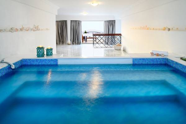 Innenpool im Mitsis Grand Hotel Beach mit blauen Fliesen und Blick auf den Balkon.