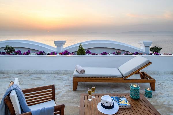 Terrasse mit Meerblick im Mitsis Grand Hotel Beach mit Loungemöbeln, Büchern und Gläsern.