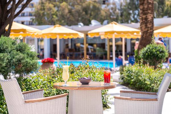 Ein Tisch im Freien mit zwei Cocktails und einem Hotel im Hintergrund.