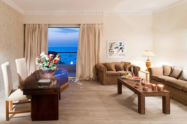 Wohnbereich im Mitsis Grand Hotel Beach mit Meerblick, Couch, Tisch, Blumen und Dekoration.