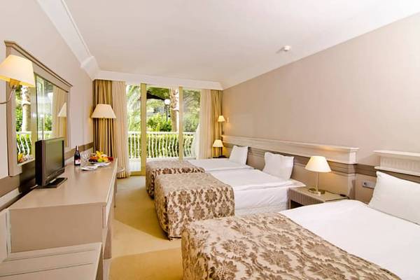 Doppelzimmer im Fantasia Hotel De Luxe mit drei Betten und Balkon.
