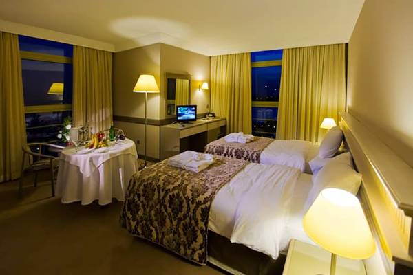 Zwei Betten im Fantasia Hotel De Luxe Zimmer mit Nachttisch und Fernseher.