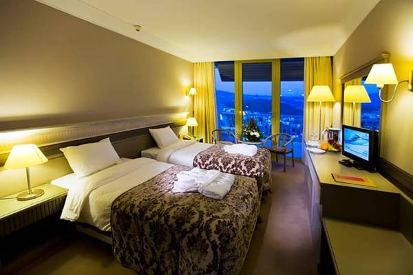 Zwei Betten im Hotelzimmer des Fantasia Hotel De Luxe mit Blick auf die Stadt.