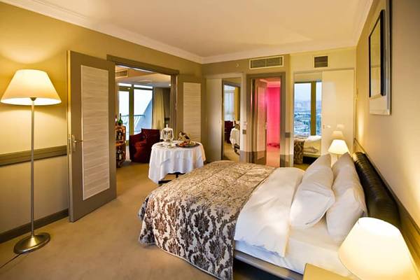 Suite-Zimmer im Fantasia Hotel De Luxe mit großem Bett, Tisch und Stadtblick.