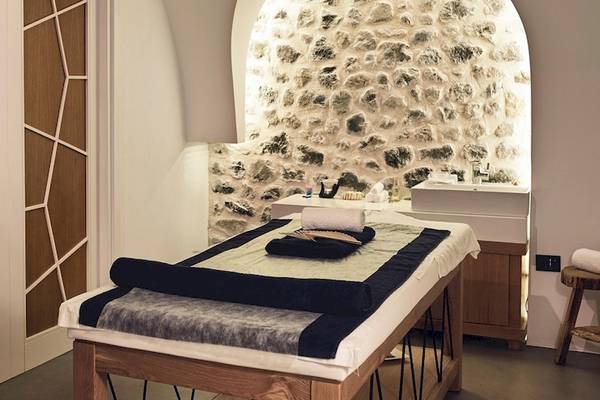 Massageraum im Santo Pure Oia Suites & Villas mit gemusterten Türen und Natursteinwand.
