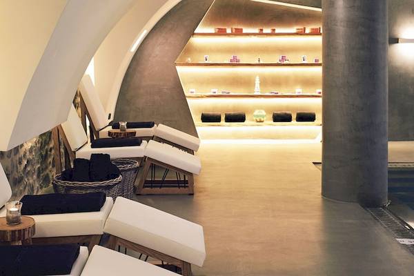 Loungebereich im Santo Pure Oia Suites & Villas mit weißen Sesseln und einer Poolansicht.