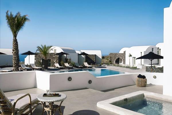Außenbereich des Santo Pure Oia Suites & Villas Hotels mit Pool, Sonnenliegen und Palmen