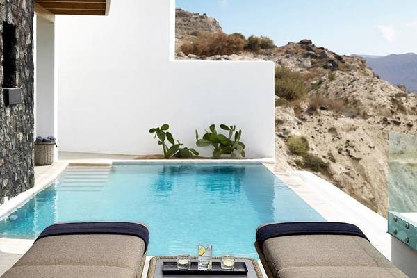 Außenpool und Terrasse des Santo Pure Oia Suites & Villas mit Blick auf einen Berg.