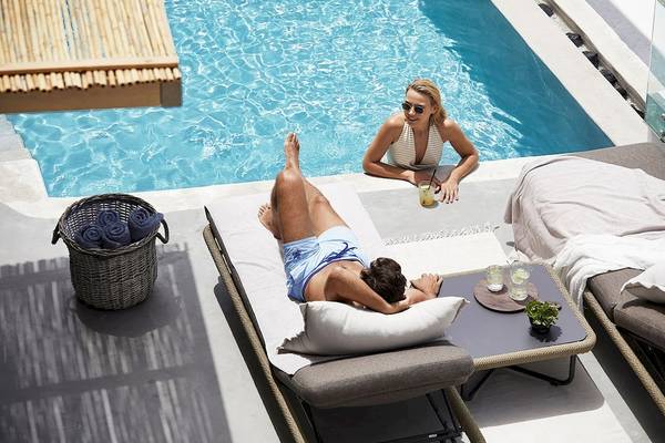 Zwei Gäste entspannen sich am Poolbereich des Santo Pure Oia Suites & Villas Hotels.