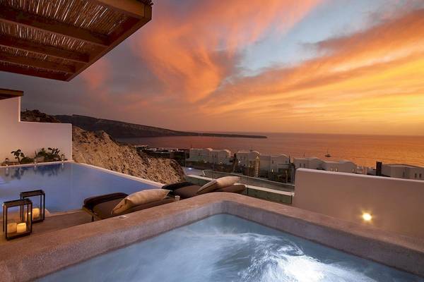 Außenpool und Loungebereich von Santo Pure Oia Suites & Villas bei Sonnenuntergang mit Blick auf das Meer.