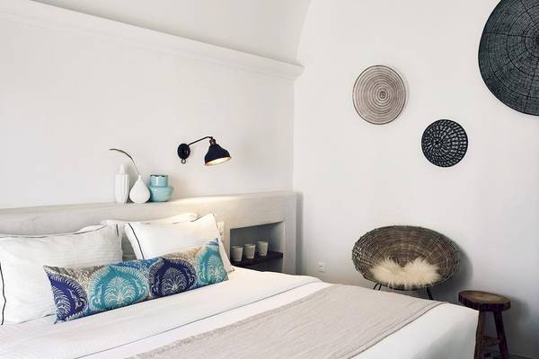 Schlafzimmer im Santo Pure Oia Suites & Villas mit weißem Bett, Kissen, Lampen und Dekor