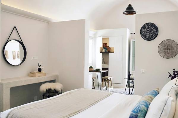 Schlafzimmer im Santo Pure Oia Suites & Villas Hotel mit weißem Bett und modernen Möbeln.
