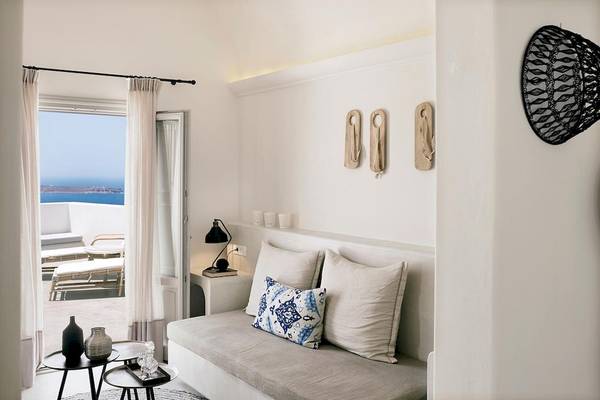 Innenraum des Santo Pure Oia Suites & Villas mit Blick auf das Meer, einem Sofa und einem Tisch.
