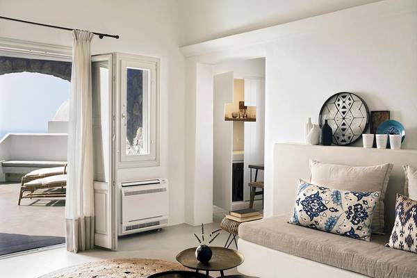 Innenansicht des Wohnbereichs der Santo Pure Oia Suites & Villas mit Blick auf den Balkon und das Meer.