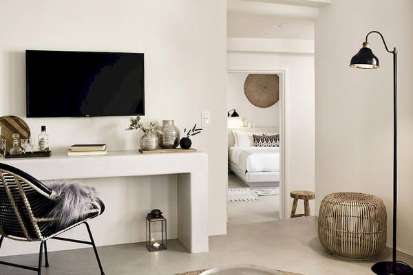 Schlafzimmer im Santo Pure Oia Suites mit minimalistischem Design, Flachbildfernseher und bequemem Bett.