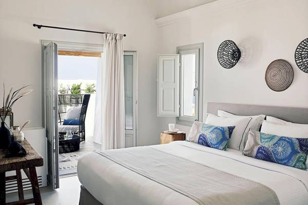 Innenansicht des Schlafzimmers im Santo Pure Oia Suites & Villas mit offenem Balkon und Blick auf den Garten.