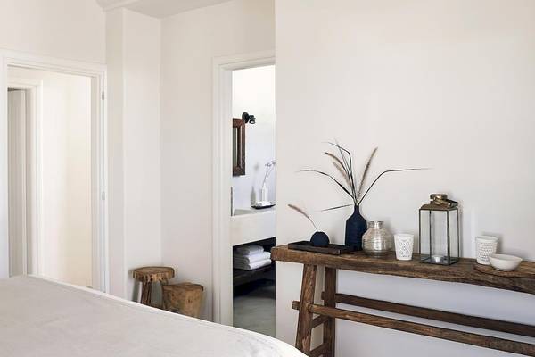 Schlafzimmer im Santo Pure Oia Suites & Villas mit weißen Wänden, einem Bett, einem Tisch und verschiedenen Dekorationsartikeln.