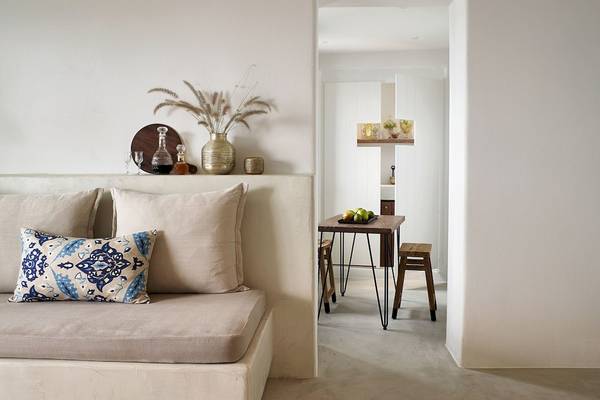 Inneneinrichtung des Santo Pure Oia Suites & Villas mit weißem Sofa, Dekor und Tisch.