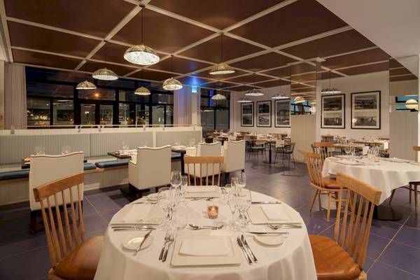 Restaurantbereich im H10 Atlantic Sunset Hotel mit weißen Tischen, Holzstühlen und Deckenlampen.