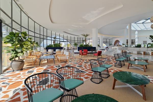 Innenraum des H10 Atlantic Sunset Hotels mit modernen Möbeln, großen Fenstern und grünen Pflanzen.