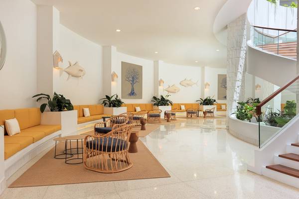 Lobby des H10 Atlantic Sunset Hotels mit gelben Sofas, runden Stühlen und Pflanzen.