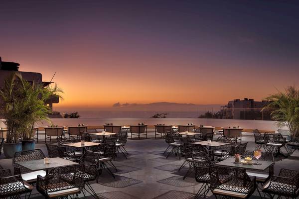 Außenterrasse des H10 Atlantic Sunset Hotels bei Sonnenuntergang mit Tischen und Stühlen.