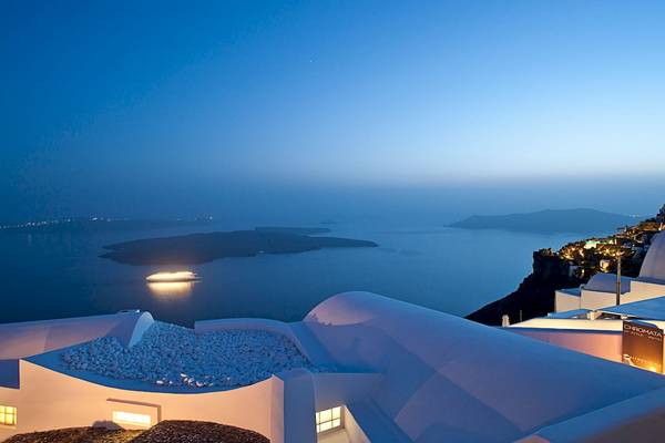 Aussicht von Katikies Chromata Santorini bei Nacht mit Blick auf das Meer und eine leuchtende Fähre.