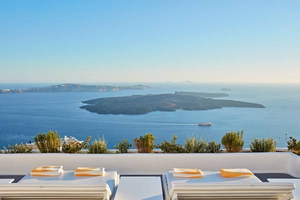 Terrasse mit Meerblick im Katikies Chromata Santorini mit zwei Liegen und gelben Handtüchern.