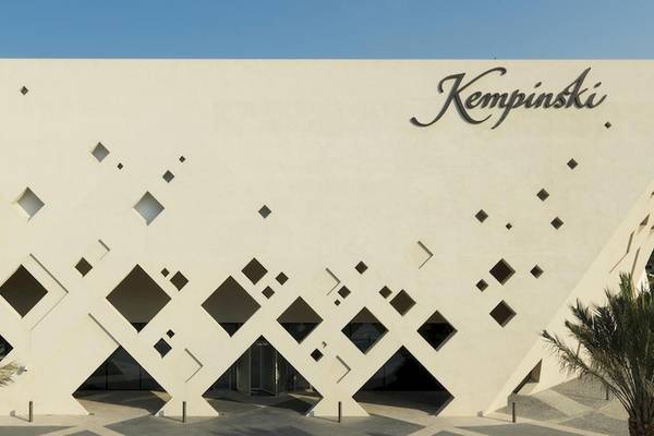 Außenansicht des Kempinski Hotels in Muscat mit moderner weißer Architektur und geometrischen Mustern.