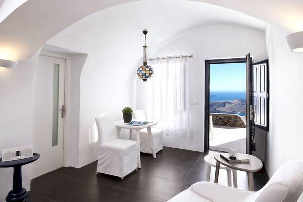 Innenraum von Katikies Chromata Santorini mit weißem Interieur, Tisch, Stühlen und Blick auf das Meer.