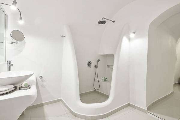 Ein Badezimmer im Katikies Chromata Santorini Hotel mit weißen Wänden und Boden.