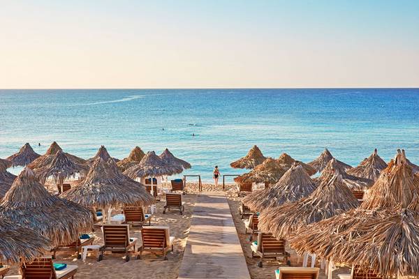Strand mit vielen Sonnenschirmen und Liegen am Grecian Bay Hotel