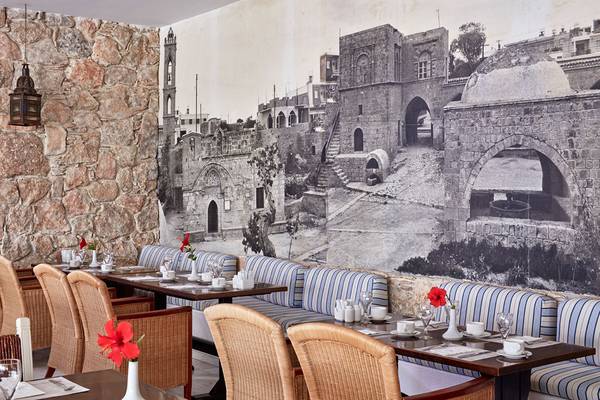 Innenansicht des Restaurants im Grecian Bay Hotel mit einer großen Wandmalerei historischer Gebäude.