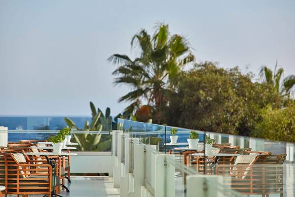 Außenterrasse des Grecian Bay Hotel mit Blick auf das Meer und Palmen