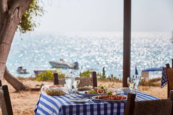 Tisch am Strand im griechischen Bay Hotel mit Blick auf das Meer und ein Boot.