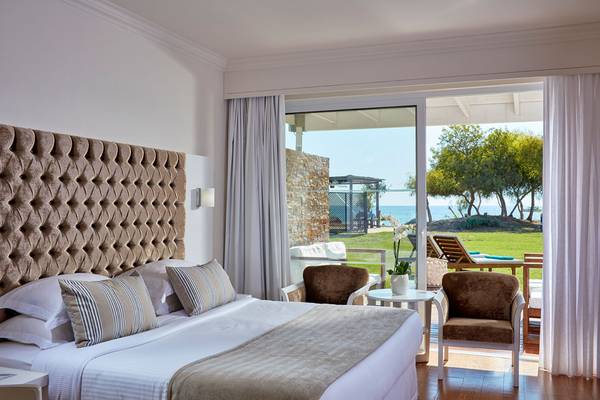 Griechisches Bay Hotel Zimmer mit Meerblick, großem Bett, bequemen Sesseln und Panoramafenstern.